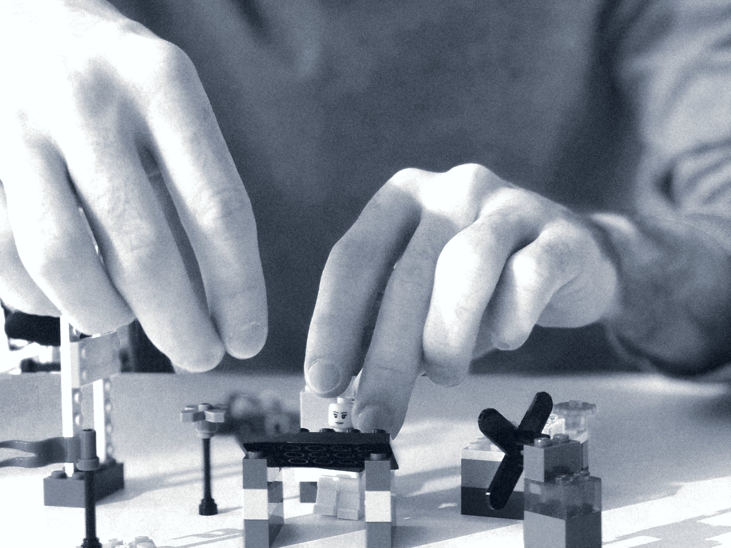 Duas mãos a construir um pequeno modelo em cima de uma mesa